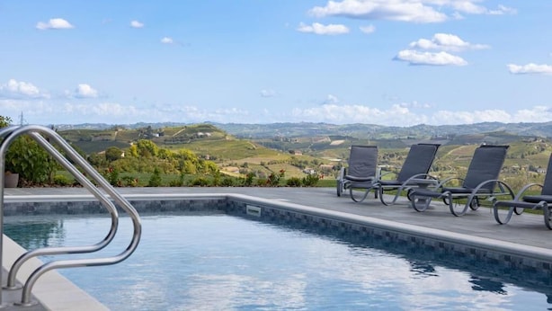 A pool with lounge chairs and a view of rolling hills. - Casa Nizza D'Oro (Castelnuovo Calcea)