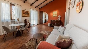 A living room with a sofa, a dining table with chairs, a fireplace, and a large mirror. - Casa Nizza D'Oro (Castelnuovo Calcea)