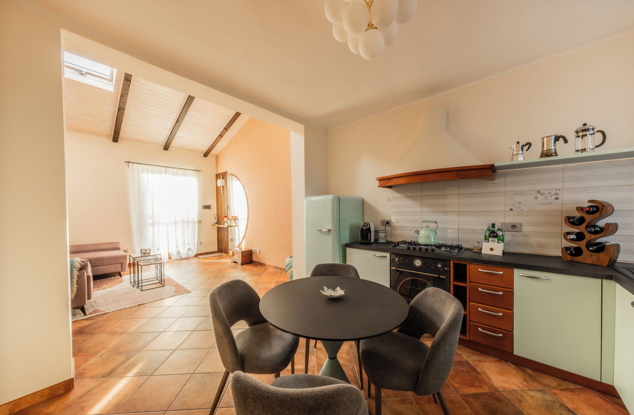 A modern kitchen with a dining area, a built-in stove, and a window with curtains.