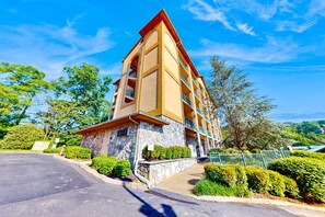 Ein mehrstöckiges Hotel mit Steinverkleidung, Balkonen und einem Parkplatz.