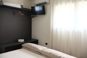 A hotel room with a bed, a TV mounted on the wall, a towel rack, and an air conditioning unit. - In a Residence, Air-conditioned, With Terrace (Marone)