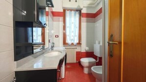 Ein kleines Badezimmer mit Waschbecken, Toilette und Duschbereich.