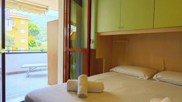 Ein Hotelzimmer mit Bett, Fenster und Blick auf ein Gebäude.