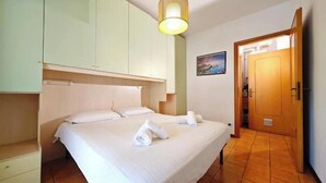 Ein Schlafzimmer mit einem Bett, einem Nachttisch, einer Holztür und einer wandmontierten Leuchte.