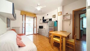 Ein Zimmer mit einem Bett, einem Tisch, einer Mikrowelle, einem Kühlschrank und einem Deckenventilator.
