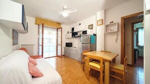 A room with a bed, a table, a microwave, a refrigerator, and a ceiling fan. - Hostdomus - Love Boat (Marina di Andora)