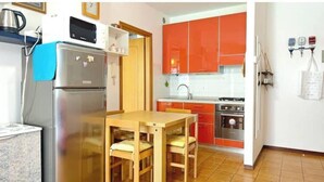 Eine kleine Küche mit Kühlschrank, Backofen und Spüle.