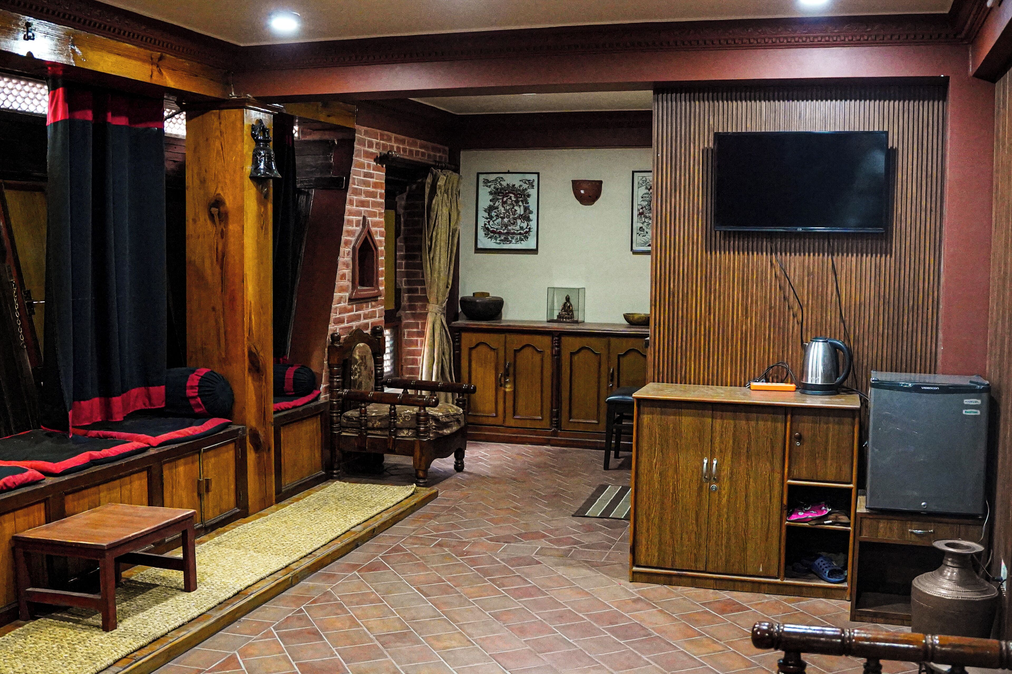 A traditional room with a sofa, wooden cabinet, television, and a fireplace.