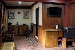 Una habitación con un armario de madera, televisor y suelo de baldosas.