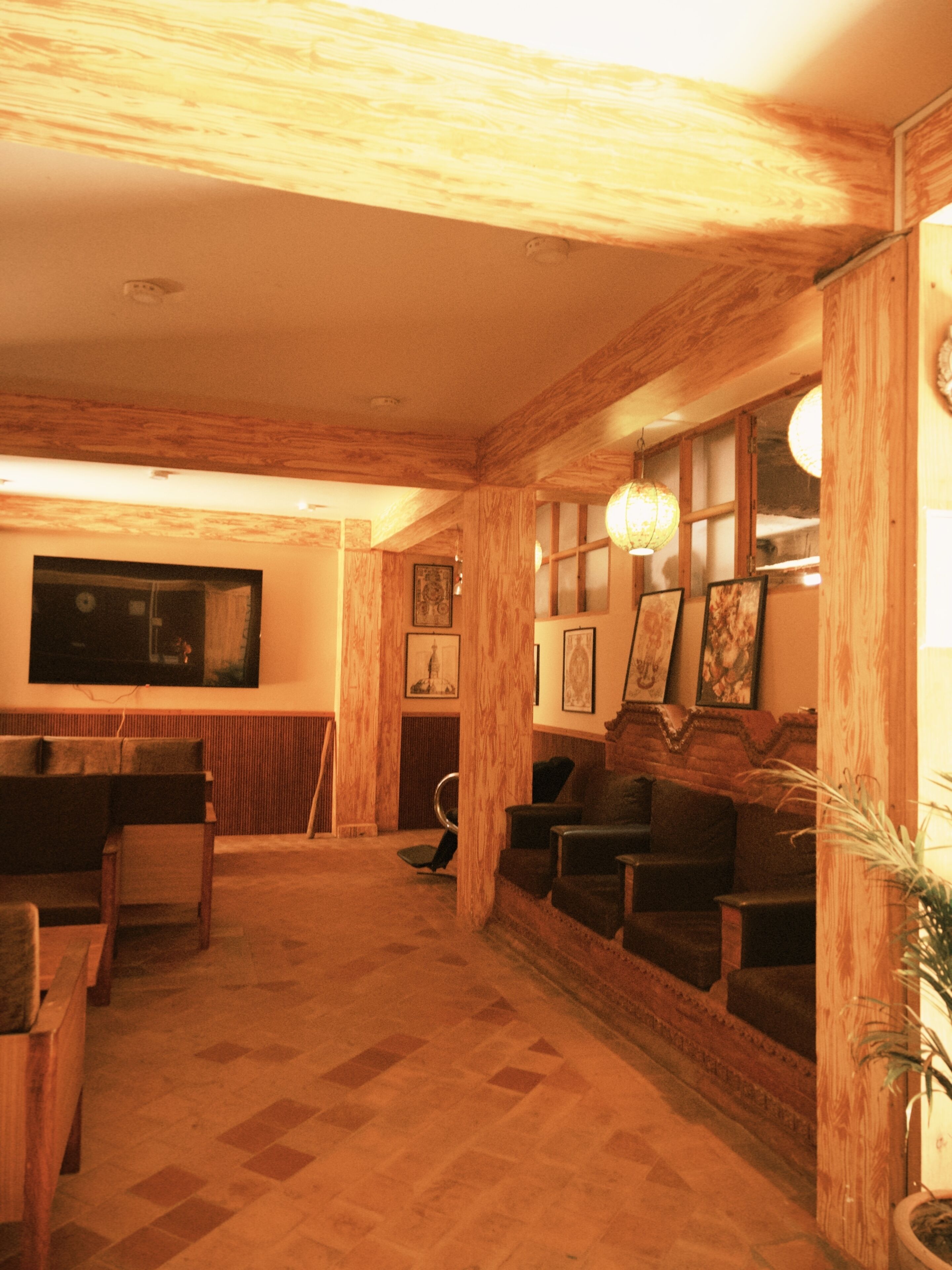 Una habitación con techo de madera, un televisor montado en la pared y una zona de estar con sofá y sillones.