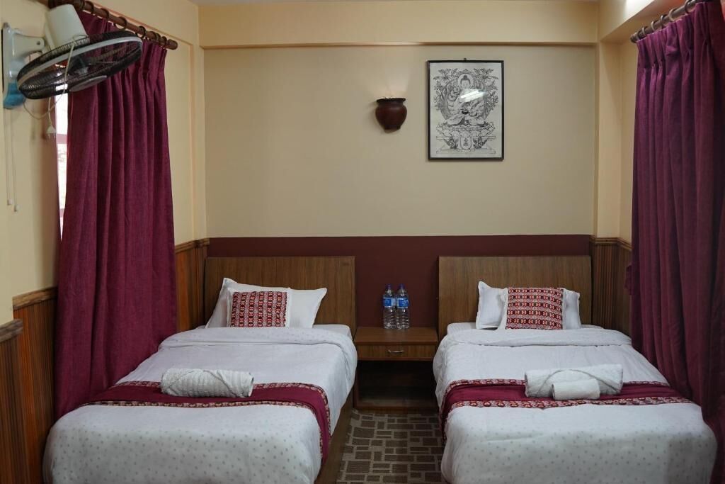 Habitación de hotel con dos camas, un calentador de pared, un dispensador de agua y un cuadro enmarcado.