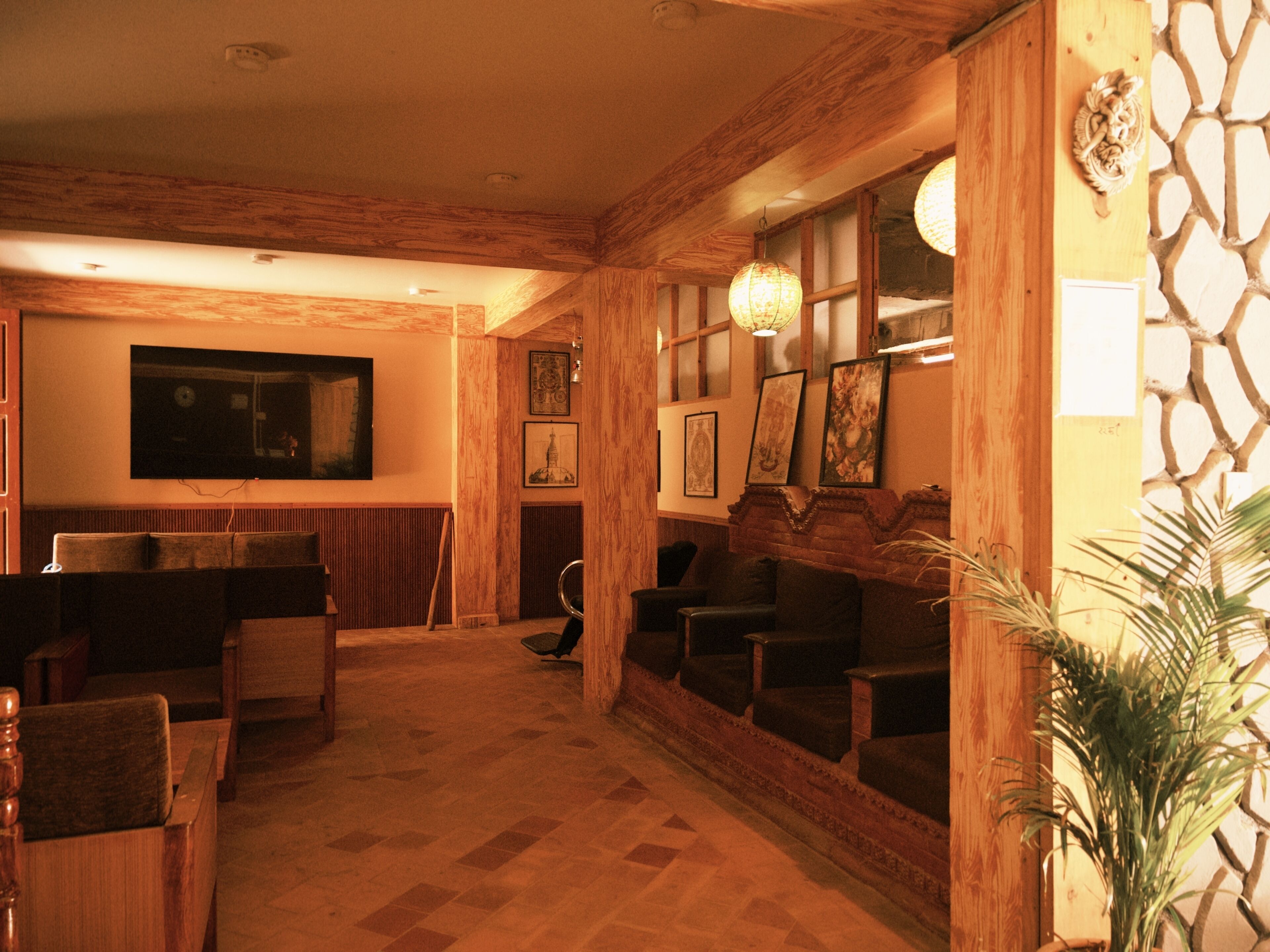 Een kamer met houten balken, een open haard, een televisie en kunstwerken in lijsten aan de wanden.