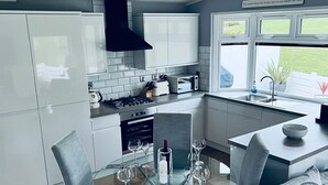 Eine moderne Küche mit weißen Schränken, einer schwarzen Dunstabzugshaube, einem Einbauofen und einem Fenster mit Blick ins Freie.