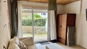 Un salon comprenant un canapé, une table basse, un meuble et une porte-fenêtre coulissante donnant sur un jardin.
