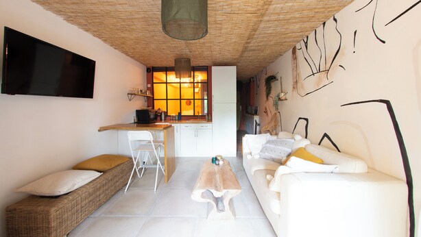 Un espace de vie compact comprenant un coin cuisine, un coin repas et un espace détente avec un canapé et des fauteuils.