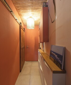 A narrow hallway with a wooden door, a white refrigerator, and a painting on the wall. - Cosy apartment 200m from Penon beach (Seignosse)