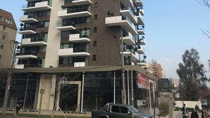 A high-rise building with multiple balconies, a clear sky, and a few pedestrians on the street. - Santiago Retreat Plus EXC Modern 2 BR in Las Condes (Santiago)