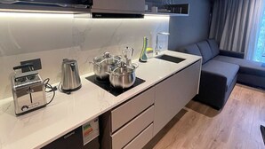Une cuisine moderne équipée d’un four à micro-ondes, d’un grille-pain, d’une bouilloire et de casseroles posées sur le plan de travail.