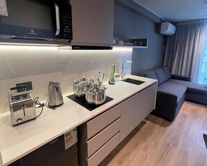 A modern kitchen with a microwave, toaster, kettle, and pots on the counter.