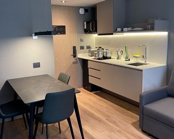 A modern kitchen with a dining area, including a table, chairs, and a microwave.