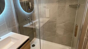 Une salle de bain moderne avec une douche à parois de verre, un lavabo blanc et un miroir.