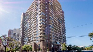 A high-rise residential building with multiple balconies, a clear sky, and surrounding greenery. - Manquehue Retreat EXC Stylish Home in Las Condes (Santiago)