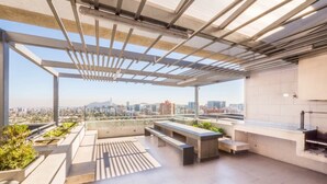 A rooftop terrace with a pergola, seating area, and a view of the cityscape. - Manquehue Retreat EXC Stylish Home in Las Condes (Santiago)