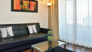 A modern living room with a black leather sofa, a glass coffee table, and a potted plant. - Manquehue Retreat EXC Stylish Home in Las Condes (Santiago)