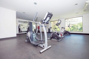 Een sportschool met cardioapparatuur, spiegels en grote ramen.