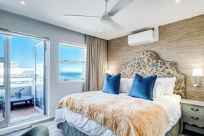 Ein Hotelzimmer mit Bett, Deckenventilator, Fenster mit Blick und Nachttisch mit Lampe.