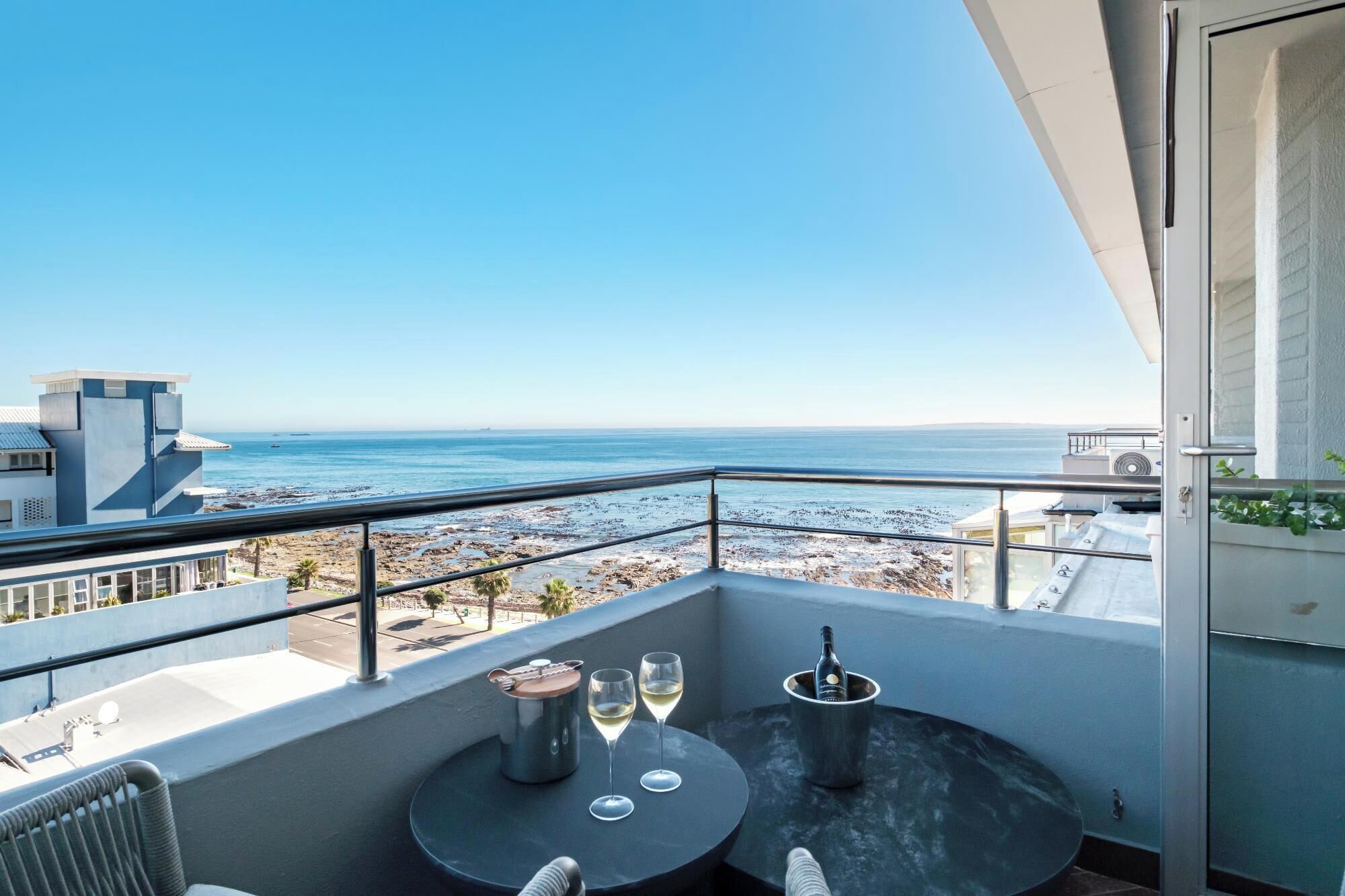 A balcony with a table, two wine glasses, and a bottle of wine.