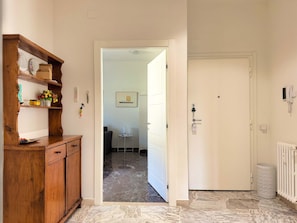 A hallway with a wooden cabinet, a white door, and a radiator. - Il Pianoforte Authentic With Balcony (Florence)