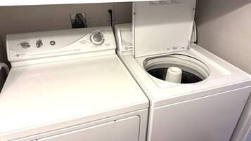 Una lavadora y secadora de carga frontal con panel de control, cable de alimentación e enchufe de pared.