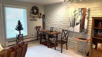 A dining area with a brick wall, a fireplace, and a small table with chairs.