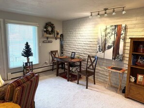 A dining area with a brick wall, a fireplace, and a small table with chairs. - EagleVail Golf Course Cozy Retreat | Ground Floor (Avon)