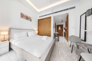 Ein modernes Hotelzimmer mit einem großen Bett, einem Schreibtisch, einem Stuhl und einem durch eine geöffnete Tür einsehbaren Badezimmer.