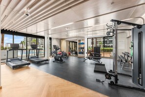 Ein modernes Fitnessstudio mit Laufbändern, Kraftgeräten und einer Spiegelwand.