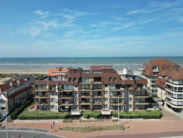 A multi-story hotel with balconies, a beach view, and a landscaped courtyard. - Family Apartment in Groenendijk (Koksijde)
