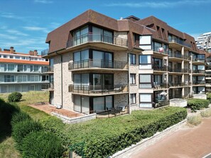 A multi-story residential building with balconies, large windows, and a brick facade. - Family Apartment in Groenendijk (Koksijde)