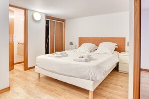 A hotel room with a bed, bedside tables, a round light fixture, and a wooden floor. - Duplex T2 (Unit 5B) overlooking Place du Capitole (Toulouse)