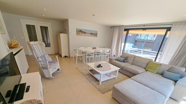 En moderne stue med sofa, sofabord, spisebord og stole.