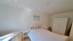 Et soveværelse med seng, sengebord, natbord og et garderobeskab.