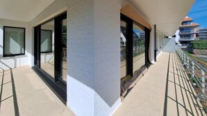 En moderne bygning med store vinduer, en balkon og udsigt til andre bygninger.