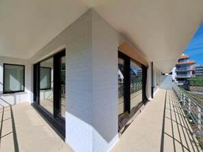 Ein modernes Gebäude mit großen Fenstern, einem Balkon und Blick auf andere Häuser.