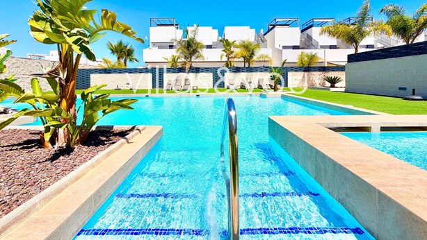 Ein Swimmingpool mit klarem, blauem Wasser, umgeben von modernen Gebäuden und Palmen.