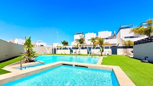 Ein Swimmingpool mit klarem, blauem Wasser, umgeben von einer gepflegten Rasenfläche und einem weißen Gebäude im Hintergrund.