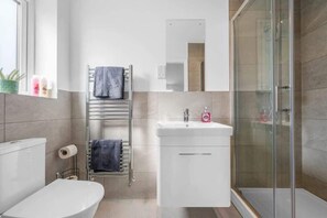 Une salle de bain moderne équipée de toilettes, d’un lavabo et d’une douche à parois en verre.