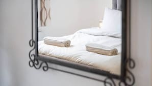 A bed with white linens and a neatly folded towel.