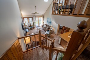 A spacious living area with a high ceiling, a dining table, and a staircase leading to an upper level. - OG22 - An Eagle Ridge Resort & Spa Rental with Full Resort Amenities and Owners Club Access! (Galena)