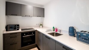 A modern kitchen with a microwave, toaster, and sink. - Bright Apartment Near Shops in Eccles Manchester (Eccles)